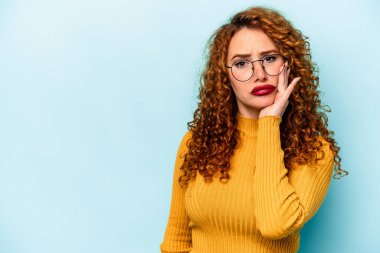 Mavi arka planda izole edilmiş genç, beyaz bir kadın üzgün ve dalgın bir şekilde fotokopi odasına bakıyor..