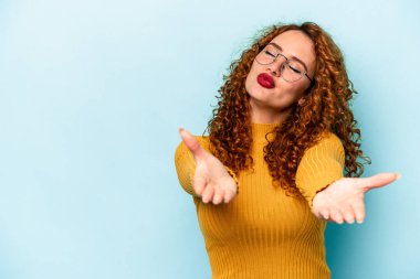 Genç, beyaz, mavi arka planda izole edilmiş dudakları kıvrılmış ve hava öpücüğü yollamak için avuç içi tutan bir kadın..