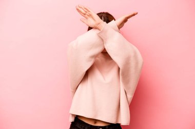 Pembe arka planda izole edilmiş genç beyaz kadın iki kolu çapraz tutuyor, inkar kavramı.