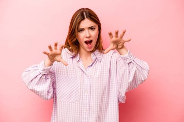 Pembe arka planda izole edilmiş genç beyaz kadın gergin elleriyle çığlık atıyor..