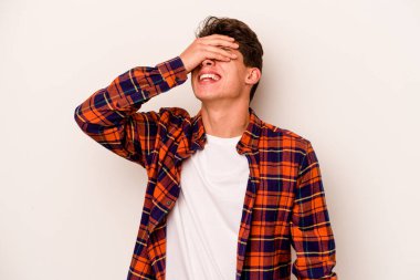 Beyaz arka planda izole olmuş genç beyaz bir adam ellerini başının üstünde tutarak neşeyle gülüyor. Mutluluk kavramı.