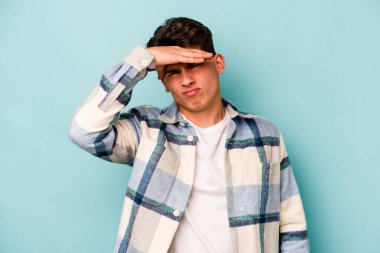 Genç beyaz adam mavi arka planda izole edilmiş tapınaklara dokunuyor ve başı ağrıyor..
