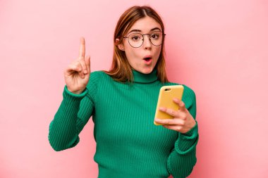 Elinde cep telefonu tutan beyaz bir kadın pembe arka planda izole edilmiş. Harika bir fikri var. Yaratıcılık kavramı..