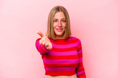Pembe arka planda izole edilmiş beyaz bir kadın. Kameraya elini uzatıp selam veriyor..
