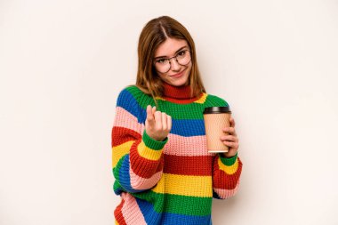 Beyaz arka planda izole edilmiş kahve taşıyan genç beyaz kadın sanki seni davet ediyormuş gibi seni işaret ediyor..