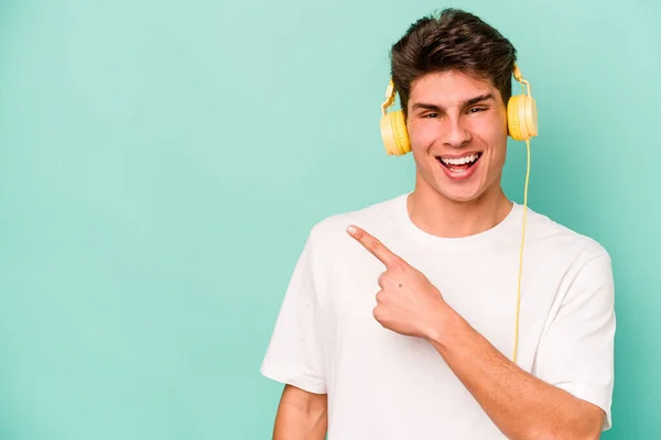 Jonge Kaukasische Man Luistert Naar Muziek Geïsoleerd Blauwe Achtergrond Lachend — Stockfoto