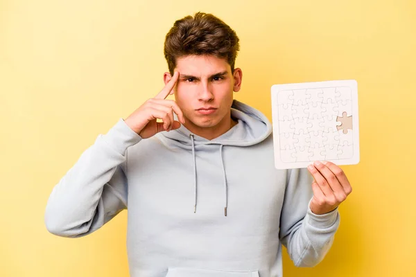 Giovane Uomo Caucasico Tenendo Puzzle Isolato Sfondo Giallo Puntando Tempio — Foto Stock