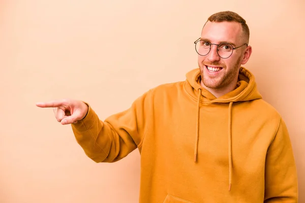 Young Caucasian Man Isolated Beige Background Smiling Cheerfully Pointing Forefinger — Stock Photo, Image