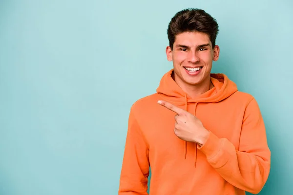 Joven Hombre Caucásico Aislado Sobre Fondo Azul Sonriendo Señalando Lado —  Fotos de Stock