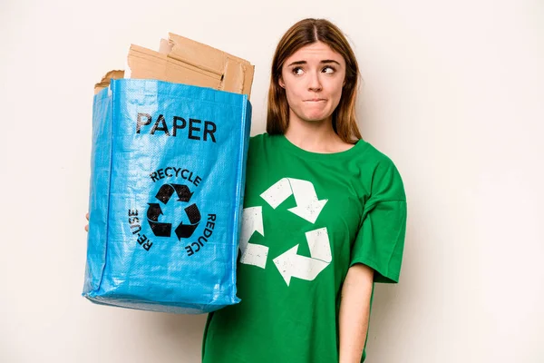 白い背景に隔離されたリサイクルのための紙の袋を持っている若い女性が混乱し 疑問と不確実性を感じています — ストック写真