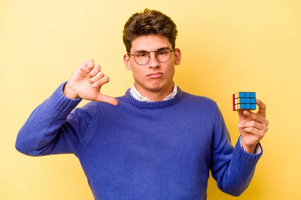 Mladý Běloch Který Drží Rubikovu Kostku Izolovanou Žlutém Pozadí Ukazuje — Stock fotografie