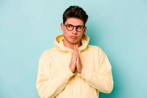 Kafkasyalı Genç Adam Mavi Arka Planda Izole Edilmiş Dua Ediyor — Stok fotoğraf