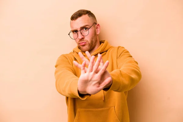 Joven Hombre Caucásico Aislado Sobre Fondo Beige Pie Con Mano — Foto de Stock