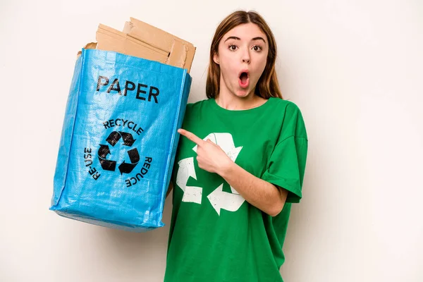Młoda Kobieta Trzyma Worek Papierem Recyklingu Odizolowany Białym Tle Wskazując — Zdjęcie stockowe