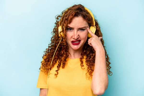 Young Ginger Woman Listening Music Isolated Blue Background Showing Disappointment — Stock Photo, Image