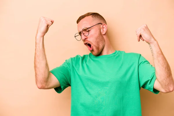 Young Caucasian Man Isolated Beige Background Raising Fist Victory Winner — Stock Photo, Image
