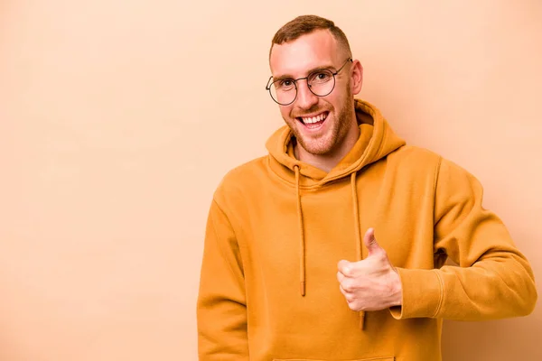 Joven Caucásico Aislado Sobre Fondo Beige Sonriendo Levantando Pulgar Hacia — Foto de Stock