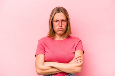 Pembe arka planda soyutlanmış beyaz bir kadın hoşnutsuzca kaşlarını çatmış, kollarını kavuşturmuş..