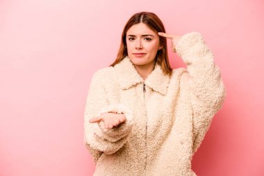 Pembe arka planda izole edilmiş beyaz bir kadın elinde bir ürün tutuyor..