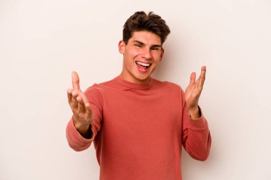 Beyaz arka planda izole edilmiş genç beyaz adam kameraya sarıldığı için kendinden emin hissediyor..