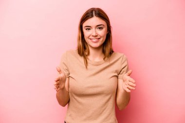 Pembe arka planda izole edilmiş beyaz bir kadın iki eliyle bir şey tutuyor, ürün sunumu..