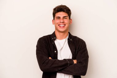 Beyaz arka planda kendini güvende hisseden, kararlılıkla kollarını kavuşturan beyaz tenli genç bir adam..