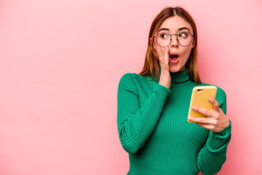 Pembe arka planda cep telefonu tutan beyaz bir kadın gizli bir sıcak fren haberi veriyor ve yan bakıyor.