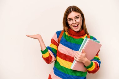 Young student caucasian woman isolated on white background showing a copy space on a palm and holding another hand on waist.