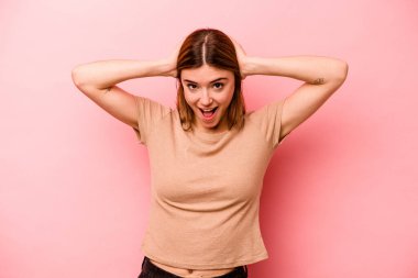 Pembe arka planda izole edilmiş genç beyaz kadın çığlık atıyor, çok heyecanlı, tutkulu, bir şeyden memnun..