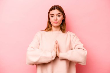 Pembe arka planda izole edilmiş genç beyaz kadın dua ediyor, bağlılık gösteriyor, dindar biri ilahi ilham arıyor..