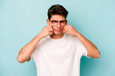 Kafkasyalı genç adam mavi arka planda izole edilmiş iki seçenek arasında şüphe duyuyor.