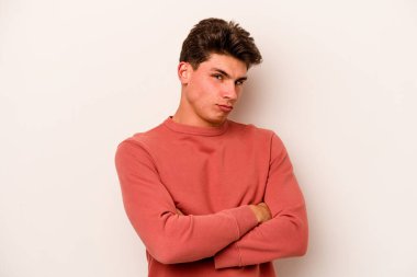 Beyaz arka planda izole edilmiş genç beyaz adam alaycı bir ifadeyle kameraya bakıyor..