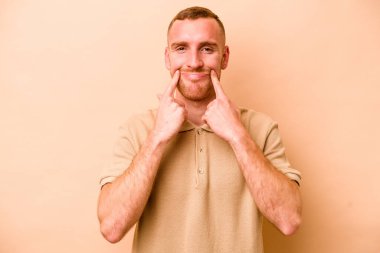 Beyazlı genç bir adam bej arka planda iki seçenek arasında kuşkulanıyor..