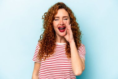 Genç, beyaz, mavi arka planda izole edilmiş bir kadın heyecanlı bir şekilde bağırıyor..