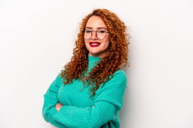 Beyaz arka planda kendini güvende hisseden, kararlılıkla kollarını kavuşturan beyaz tenli genç bir beyaz kadın..