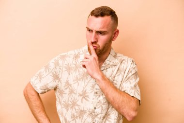 Beyazlı genç bir adam bej arka planda izole edilmiş bir şekilde sır saklıyor ya da sessizlik istiyor..