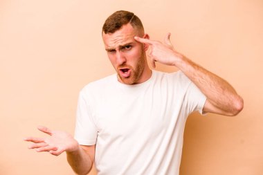 Beyazların arka planında izole edilmiş genç beyaz bir adam işaret parmağıyla hayal kırıklığı jesti yapıyor..