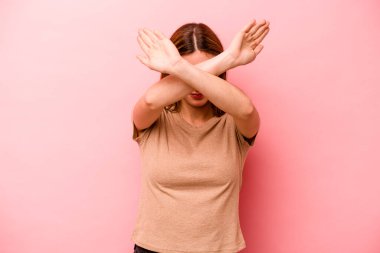 Pembe arka planda izole edilmiş genç beyaz kadın iki kolu çapraz tutuyor, inkar kavramı.