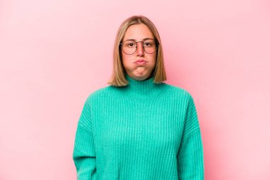 Pembe arka planda izole edilmiş genç beyaz kadın yanakları patlatıyor, yorgun bir ifade takınıyor. Yüz ifadesi kavramı.