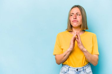 Kafkasyalı genç bir kadın mavi arka planda izole edilmiş bir plan kuruyor, bir fikir kuruyor..