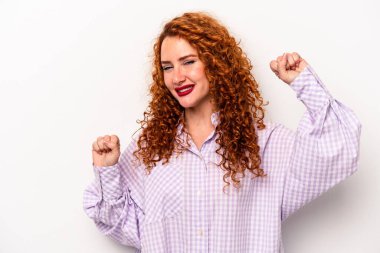 Beyaz arka planda soyutlanmış genç, beyaz tenli bir kadın özel bir günü kutluyor, atlıyor ve enerji ile kollarını kaldırıyor..