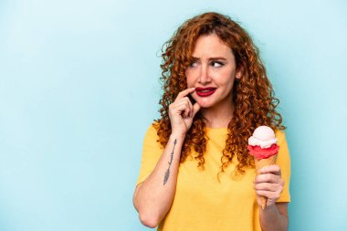 Mavi arka planda izole edilmiş dondurmayı tutan genç kızıl kadın rahatlamış fotokopi odasına bakan bir şey düşünüyor..