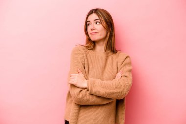 Pembe arka planda izole edilmiş genç beyaz kadın hedeflere ve amaçlara ulaşma hayali kuruyor.
