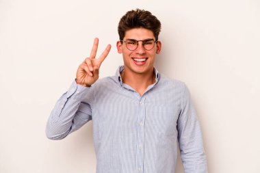Beyaz arka planda izole edilmiş genç beyaz adam iki numarayı parmaklarıyla gösteriyor..