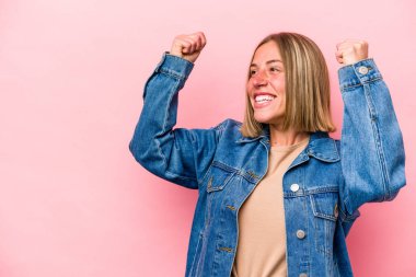 Pembe arka planda izole edilmiş beyaz bir kadın zaferden sonra yumruğunu kaldırıyor, kazanan konsept.