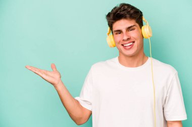 Mavi arka planda izole edilmiş müzik dinleyen beyaz bir adam bir palmiye üzerinde fotokopi alanı ve belinde başka bir el tutarken görülüyor..