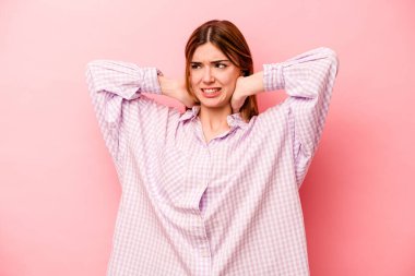 Genç, beyaz bir kadın pembe arka planda izole edilmiş. Durağan yaşam tarzından dolayı boyun ağrısı çekiyor..