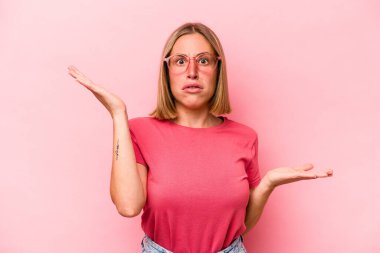 Pembe arka planda soyutlanmış beyaz bir kadın. Kafası karışmış ve omuz silkiyor. Kopya alanını tutmak için..