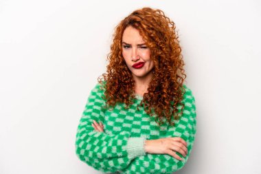 Beyaz arka planda izole edilmiş genç, beyaz tenli, hoşnutsuzca kaşlarını çatan, kollarını kavuşturan bir kadın..