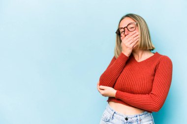 Mavi arka planda soyutlanmış genç beyaz kadın gülüyor, kaygısız, doğal duygu..